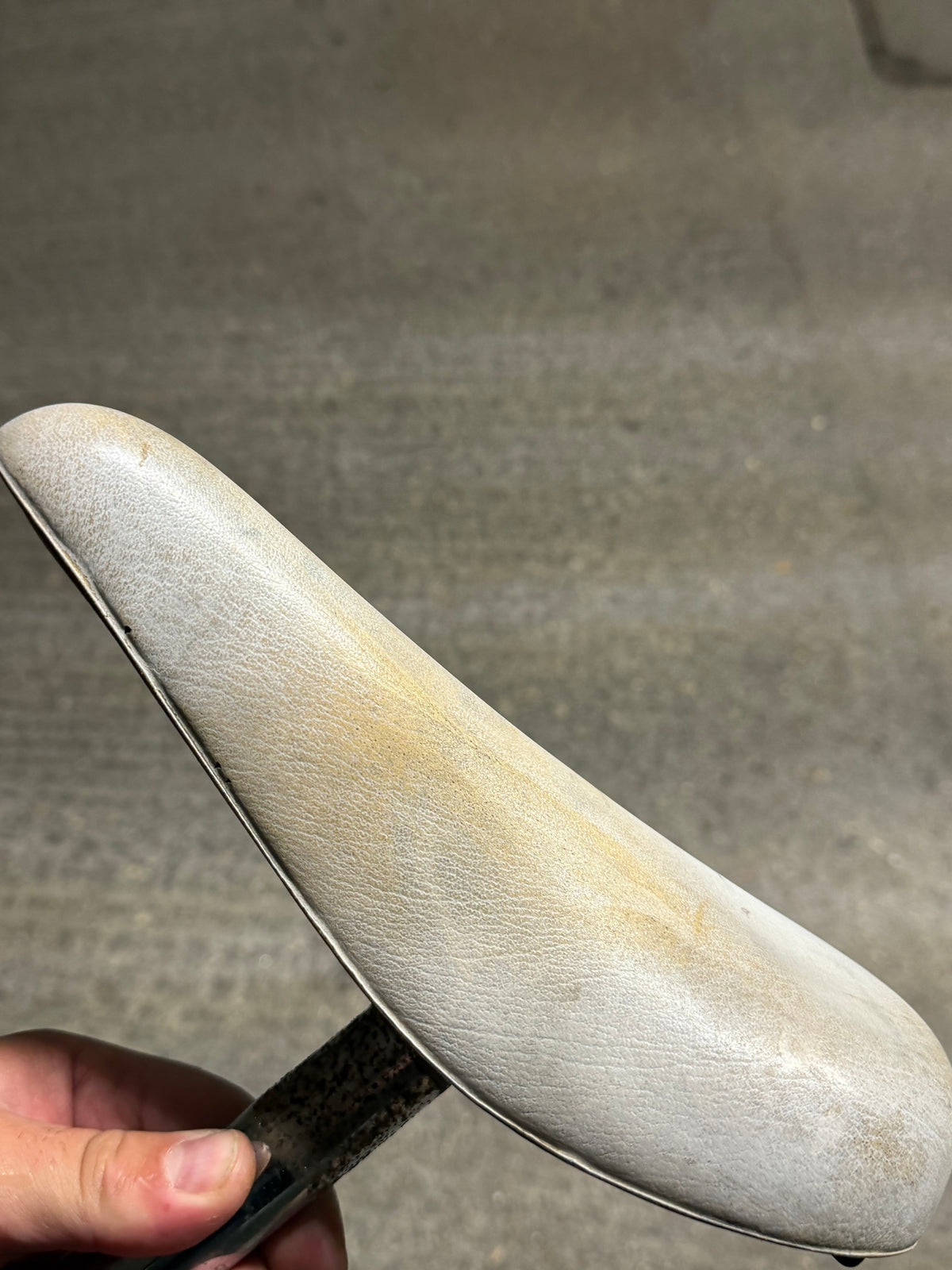 Side profile of white retro saddle with visible discolouration
