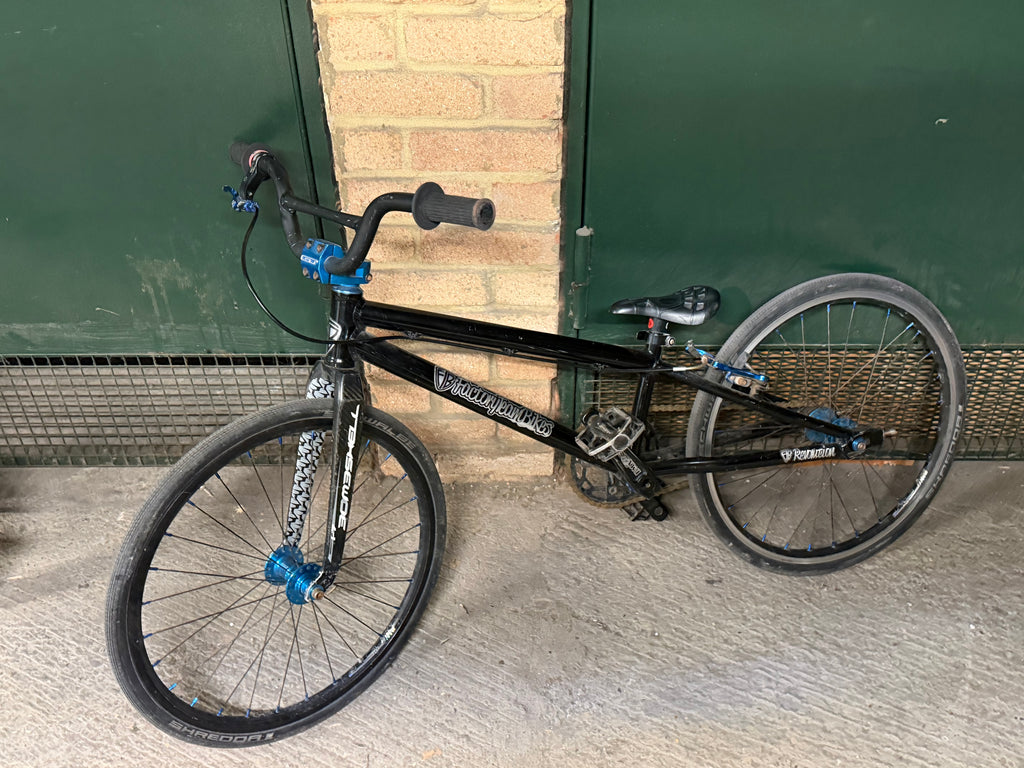 Side view of black Factory Team Bikes kids' BMX with blue hubs