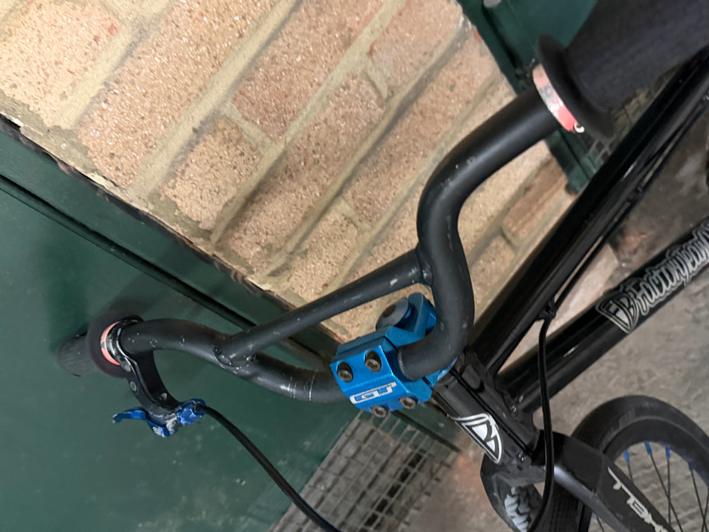 Black BMX handlebars and blue stem viewed from above
