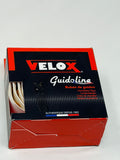 A box of Velox Guidoline handkerchief tape, showing the red and black packaging with a small window revealing the white tape inside.