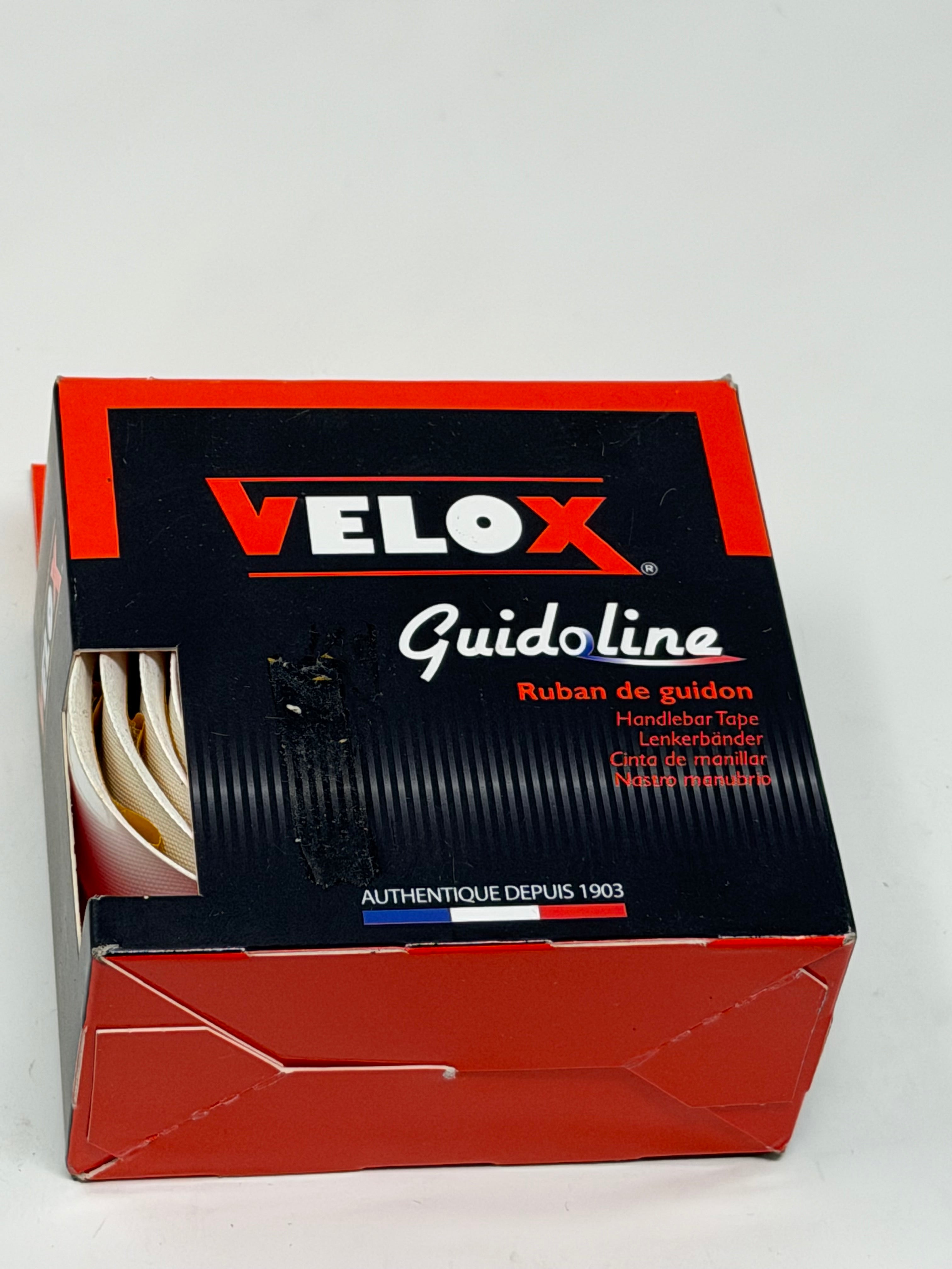 A box of Velox Guidoline handkerchief tape, showing the red and black packaging with a small window revealing the white tape inside.